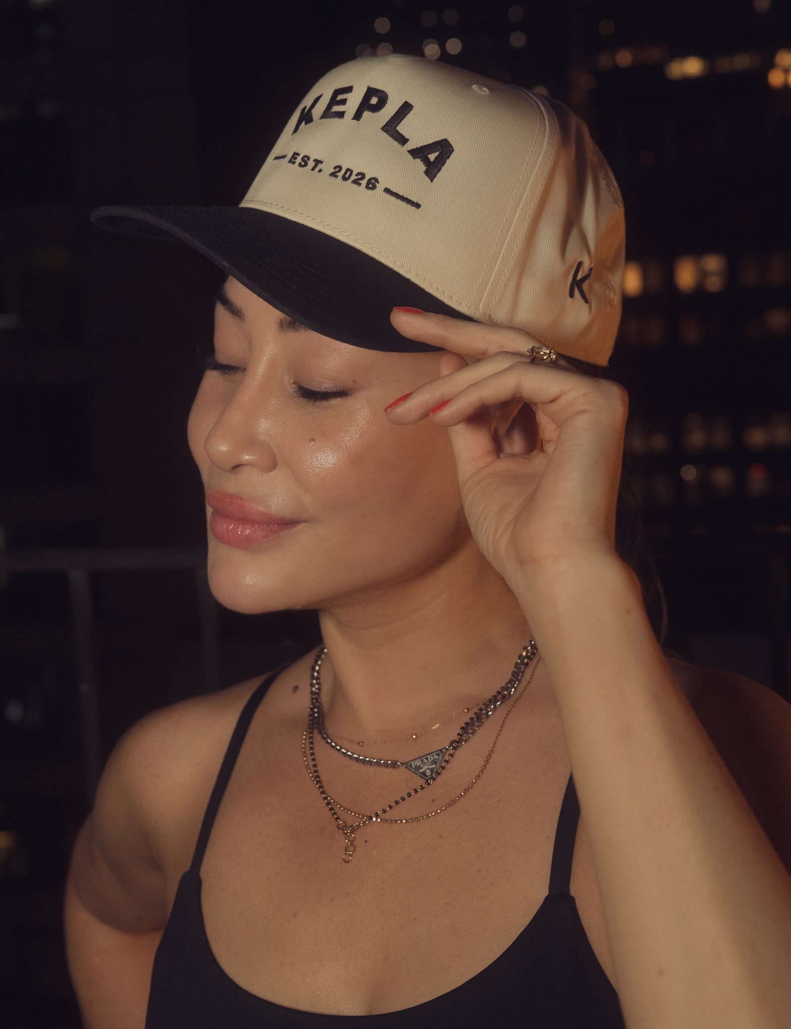 Close-up of the Kepla cap at night: KEPLA EST. 2026 embroidered on the natural crown, black brim, K monogram on the side.